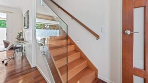 Un interior moderno con una escalera de madera, una puerta de cristal y un escritorio con una silla.
