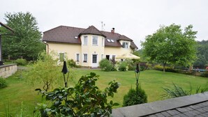 Une maison à deux étages, avec un toit recouvert de tuiles, une pelouse bien entretenue et un pot de fleurs en premier plan.