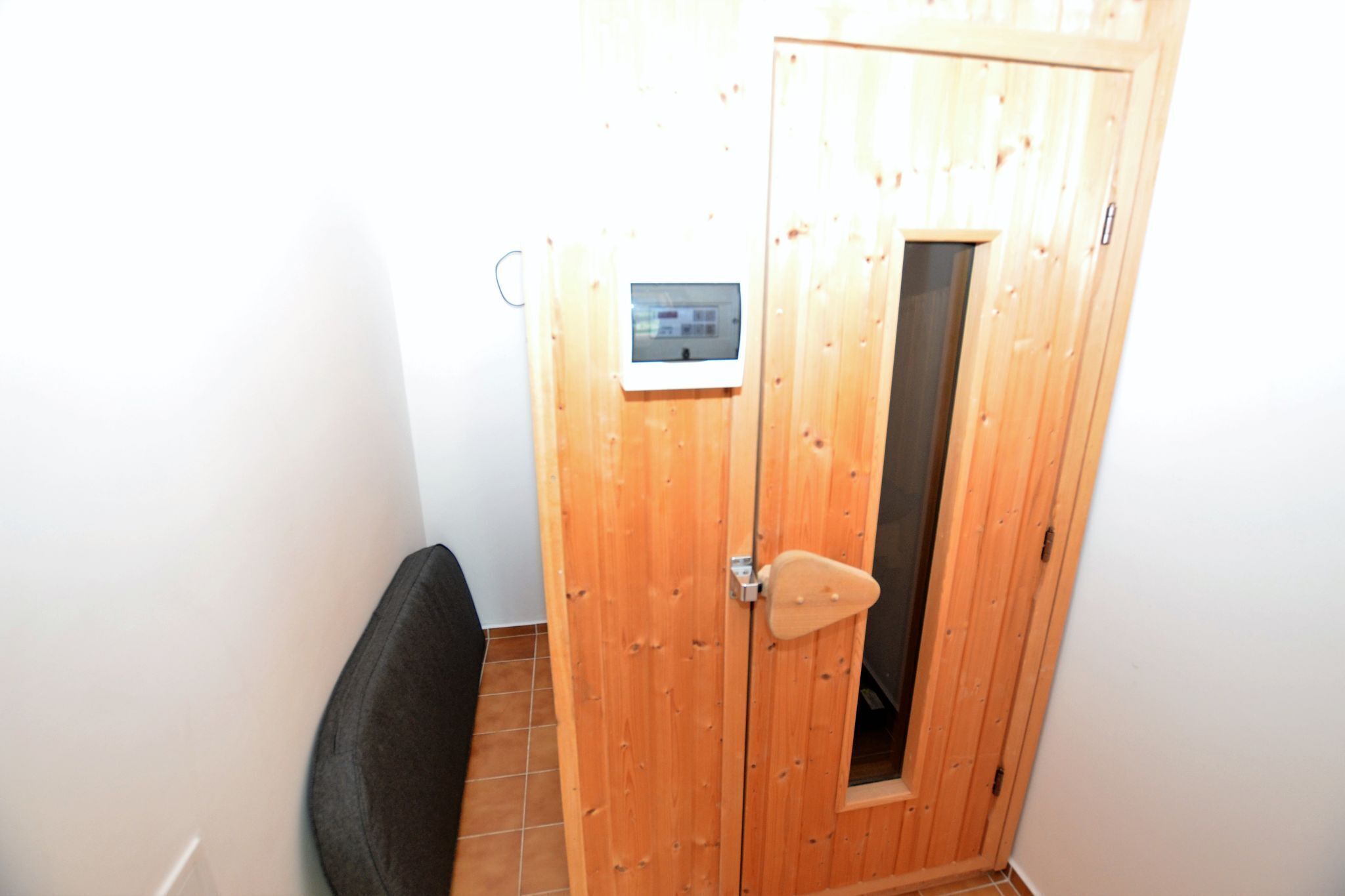 Eine Holztür mit kleinem Fenster und Bedienfeld.