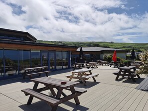 Une terrasse extérieure avec des tables de pique-nique en bois et des parasols, offrant une vue sur un paysage pittoresque.
