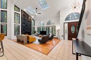 A spacious living room with a stone wall, large windows, and a fireplace.