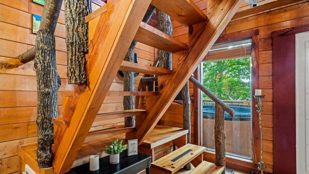 Eine Holztreppe mit rustikalem Design, die zu einem Raum mit Fenster und Tür führt.
