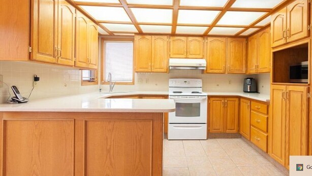 Une cuisine avec des meubles en bois, une cuisinière blanche et un grand îlot central doté d’un évier.