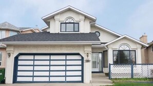 Une maison à deux étages avec un garage, une porte d’entrée et un petit porche.