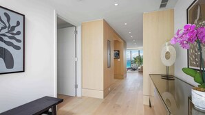 Un moderno vestíbulo de hotel con piso de madera, un banco, una mesa de vidrio y una obra de arte enmarcada en la pared.