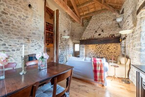 Une pièce rustique aux murs de pierre, avec une table à manger en bois, des chaises, un canapé et une cheminée.