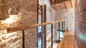 Un intérieur en pierre avec un escalier en bois et une vue sur l’extérieur.