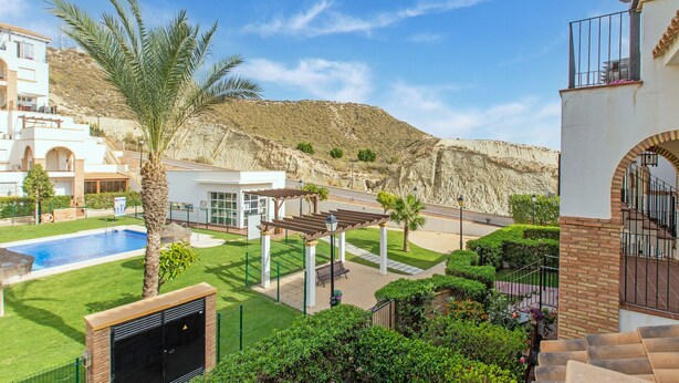 Zona residencial con piscina, palmeras y vistas a la montaña.