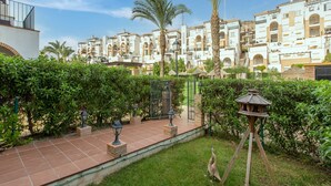 Un patio con baldosas, palmeras y un comedero para pájaros.
