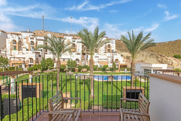 Zona residencial con piscina, palmeras y vistas a edificios de apartamentos.