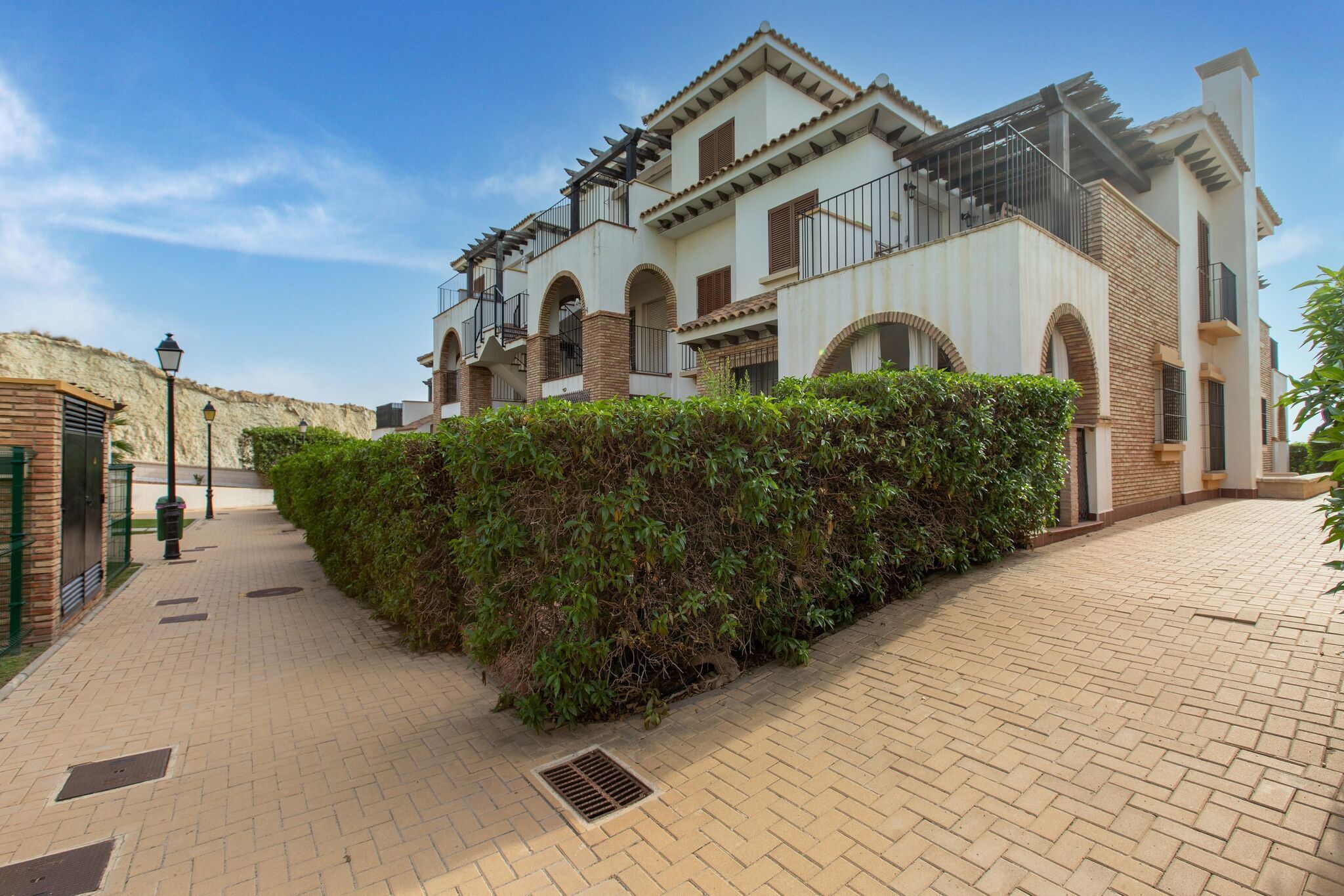 A two-story building with a brick facade, arched windows, and a balcony with metal railings.