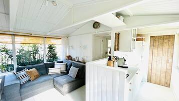 Een moderne zithoek met een grijze modulaire bank, een houten deur en een keukenblad.