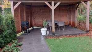 Un espacio al aire libre cubierto con una parrilla, una mesa con sillas y una planta en maceta.
