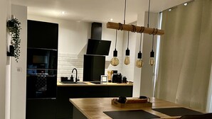 A modern kitchen with a central island, black appliances, and pendant lighting.