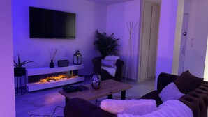 A modern living room with a flat-screen TV, a fireplace, a sofa, and a coffee table.