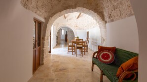 Un pasillo de paredes de piedra que conduce a un comedor con mesa y sillas.