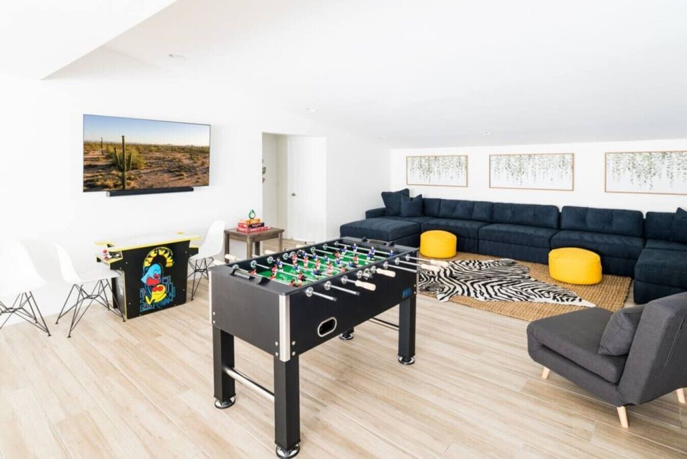 Ein modernes Wohnzimmer mit Tischfußball, einer Sofagarnitur und einem Gemälde an der Wand.