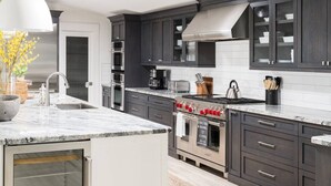 Una cocina moderna con armarios oscuros, electrodomésticos de acero inoxidable y encimera de mármol.