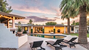 Una casa moderna con piscina, mobiliario exterior y un patio.