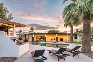 Ein modernes Haus mit Swimmingpool, Sitzgelegenheiten im Freien und einer Terrassenfläche.