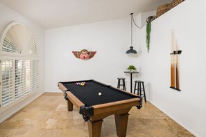 A pool table in a room with a white wall, a decorative angel painting, and a hanging plant. - Adobe Villa, Private Pool, Hiking Trails Nearby (Scottsdale)