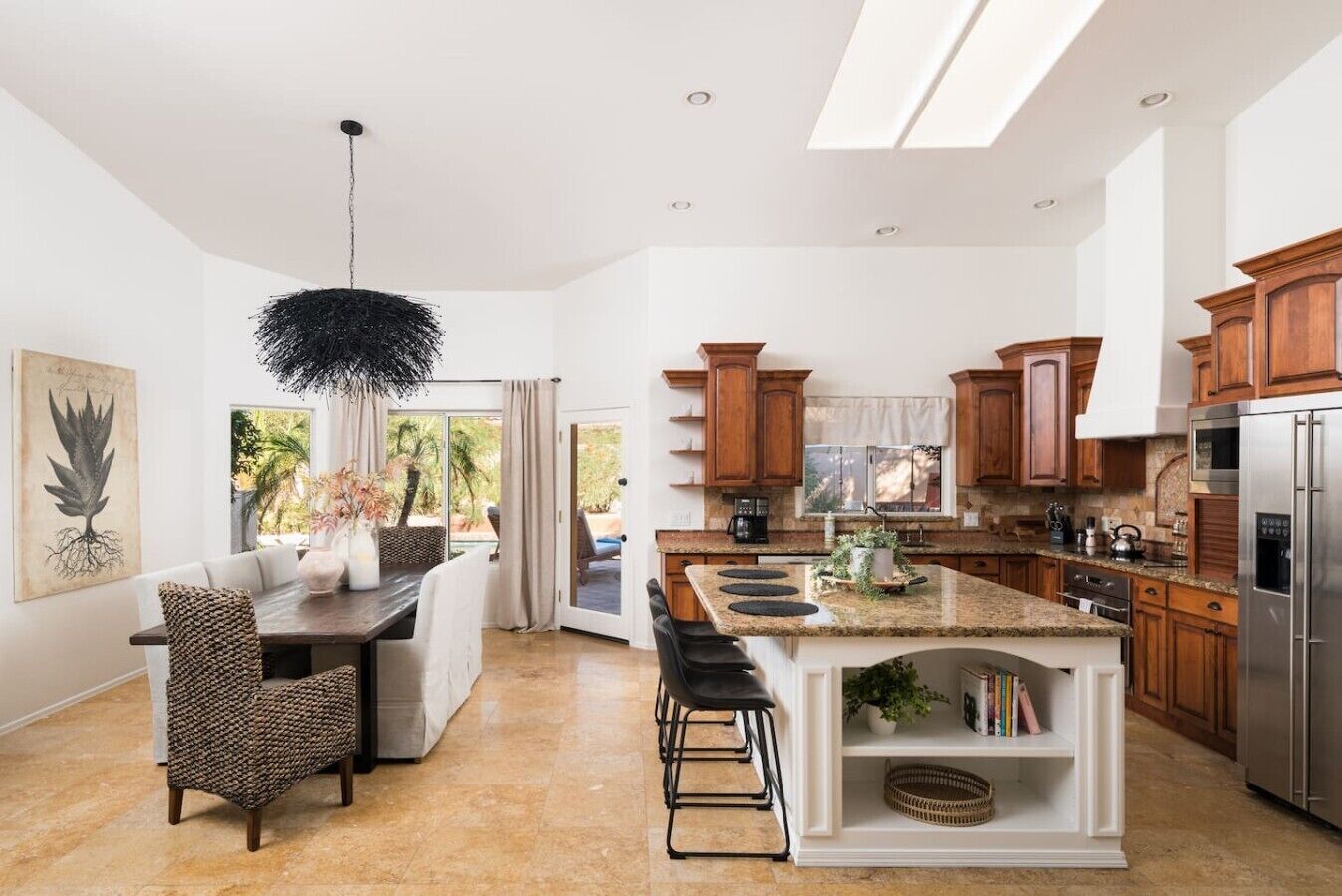 A modern kitchen with a central island, wooden cabinets, and a stainless steel refrigerator.