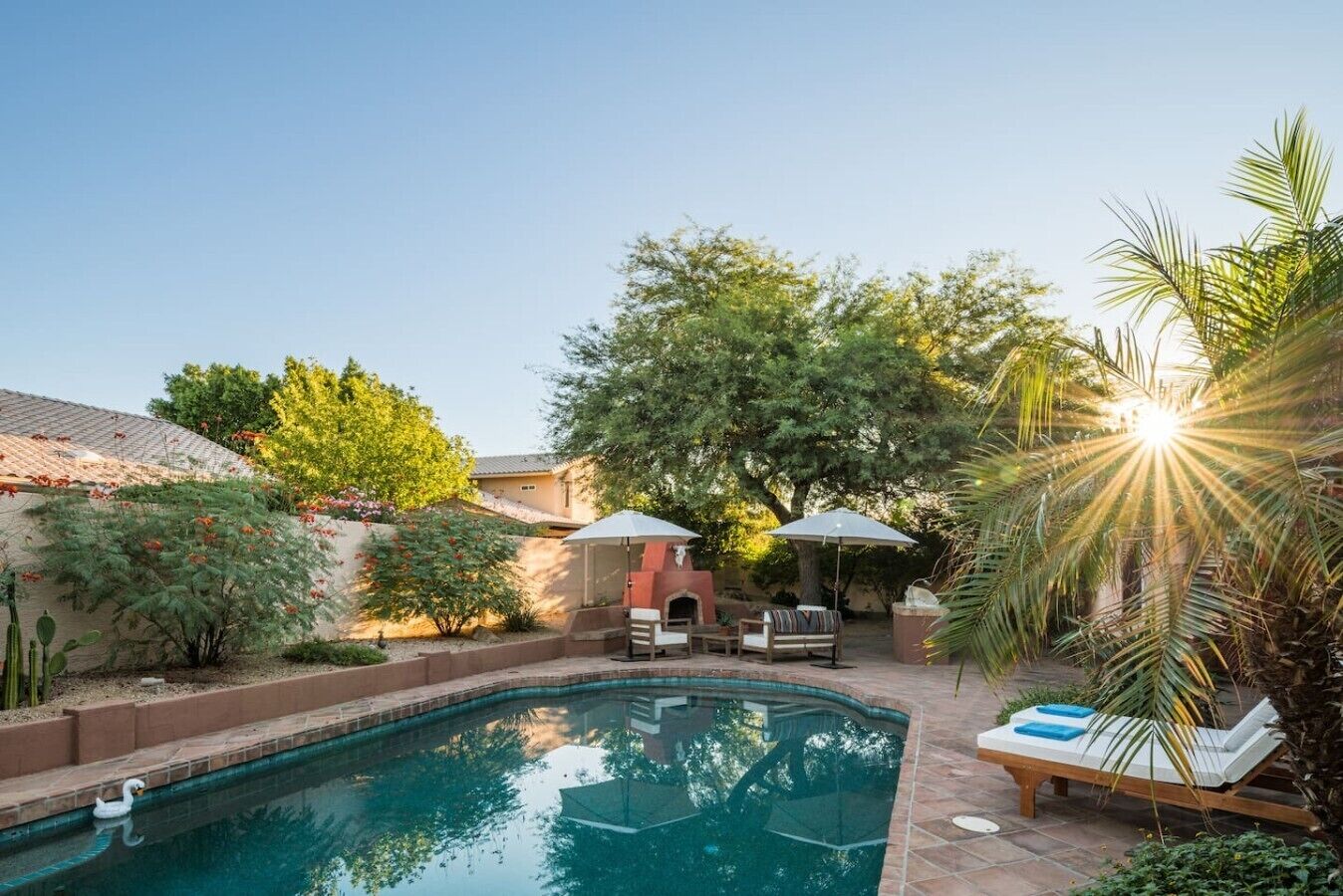A backyard with a swimming pool, a barbecue area, and outdoor seating.