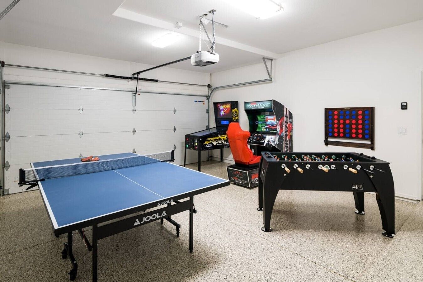 A room with a ping pong table, a foosball table, and two arcade machines.