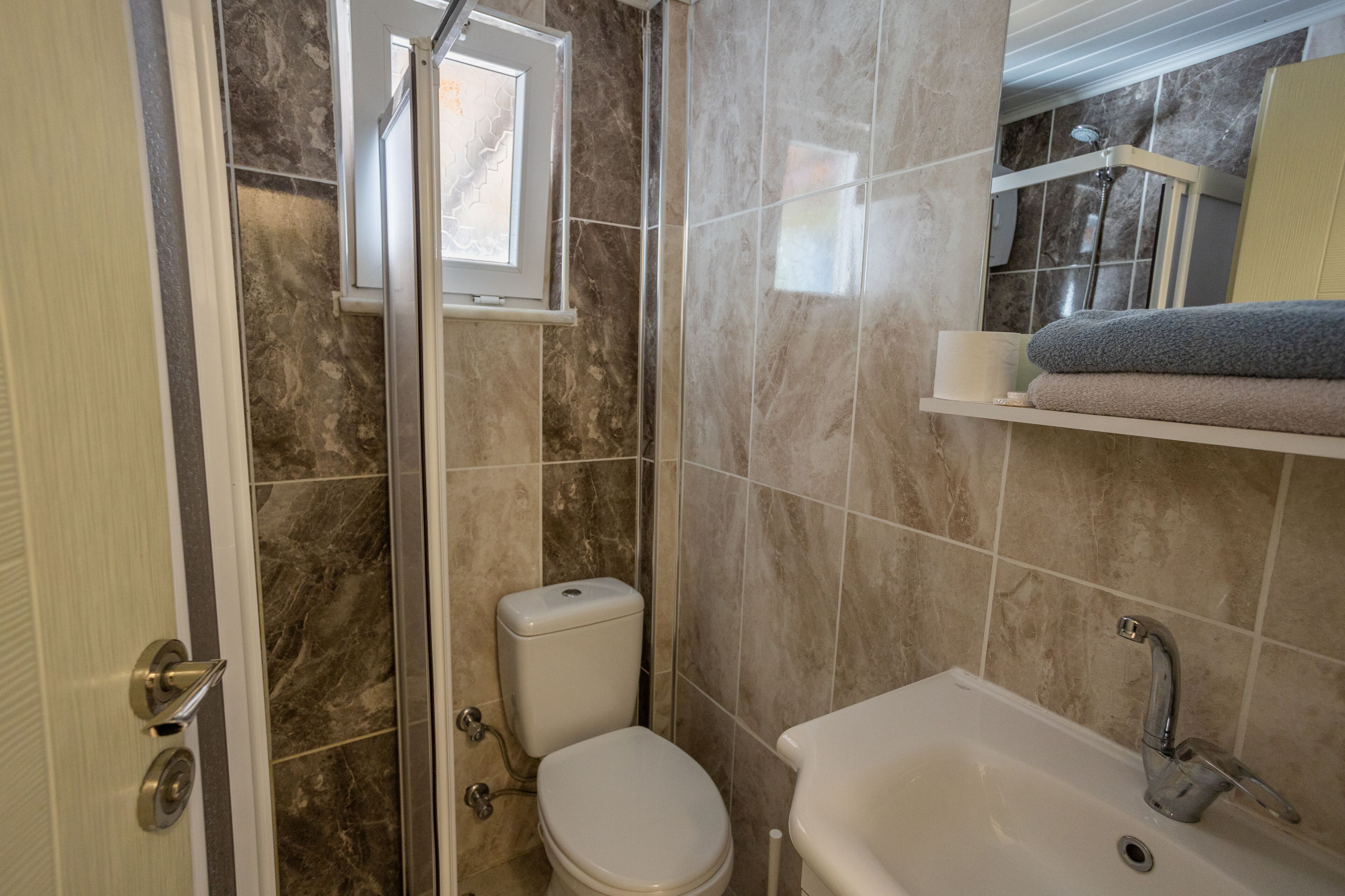 Une salle de bain avec douche, toilettes et lavabo.