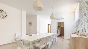 A modern dining area with a white table and chairs, pendant lighting, and a clock on the wall. - 3081 Villa Il Tulipano Verde by Barbarhouse (Putignano)