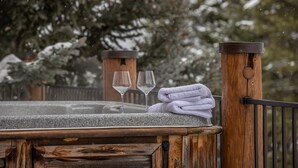 A wooden deck with a stone hot tub, two glasses, and a folded towel.