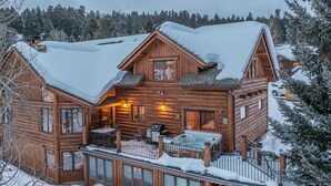 A log cabin with a balcony, a hot tub, and a dining area.