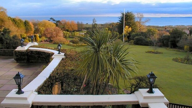 A landscaped garden with a view of the sea, stone walls, and lamp posts.