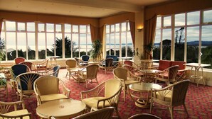 A spacious indoor seating area with wicker furniture and large windows offering a view of the outdoors.