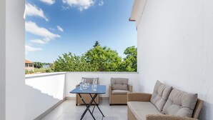 A balcony with a table and chairs, a view of trees and a body of water, and a white wall. - 3 bedroom stunning apartment in Medulin (Medulin)