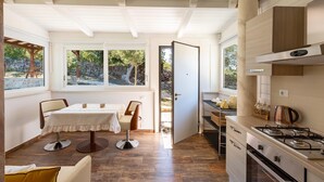 Una cocina moderna con estufa a gas, armarios de madera y un comedor con mesa y sillas.