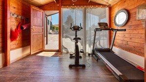 Una habitación de madera con una cinta de correr, una bicicleta estática y un espejo en la pared.