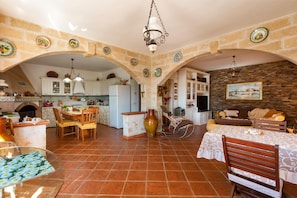 Una cocina amplia con un arco, un comedor con mesa y sillas, y una sala de estar con sofá y un cuadro en la pared.