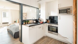Una cocina moderna con armarios blancos, horno integrado, microondas y cafetera.