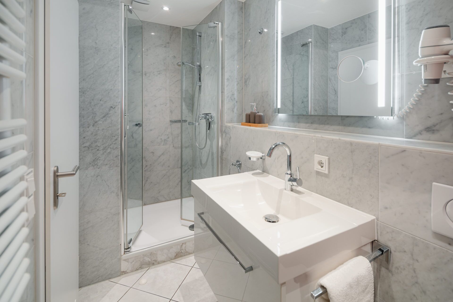 Un bany modern amb dutxa de vidre, un lavabo blanc i un mirall sobre el lavabo.