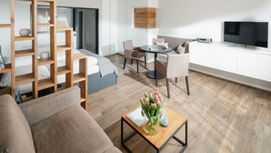 Una sala de estar moderna con un sofá, una mesa de centro y un televisor. Hay un comedor con sillas y una mesa.