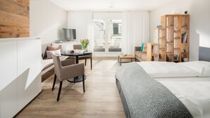 Una habitación de hotel moderna con cama, un escritorio con silla, televisión y estantería.