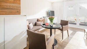 A modern living room with a sofa, two armchairs, a coffee table, and a TV. - // Strandzeit 13 // (Norderney)