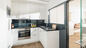 A modern kitchen with white cabinets, a black countertop, and stainless steel appliances. - // Strandzeit 13 // (Norderney)