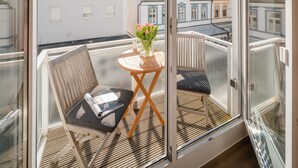 A balcony with a wooden table, two chairs, and a vase of flowers. - // Strandzeit 13 // (Norderney)