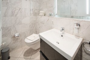 Une salle de bain moderne avec un lavabo blanc, un miroir et des toilettes.