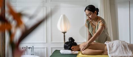 Un cuarto de spa con una camilla de masaje, un lavamanos y una lámpara.