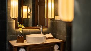 A bathroom with a round sink, wooden vanity, and two wall-mounted lights.
