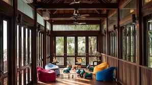 A spacious room with large windows, wooden beams, and ceiling fans. - The Anam Mui Ne (Mui Ne)