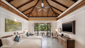 Habitación de hotel con dos camas, un ventanal con vistas a palmeras, un ventilador de techo y un televisor de pantalla plana.